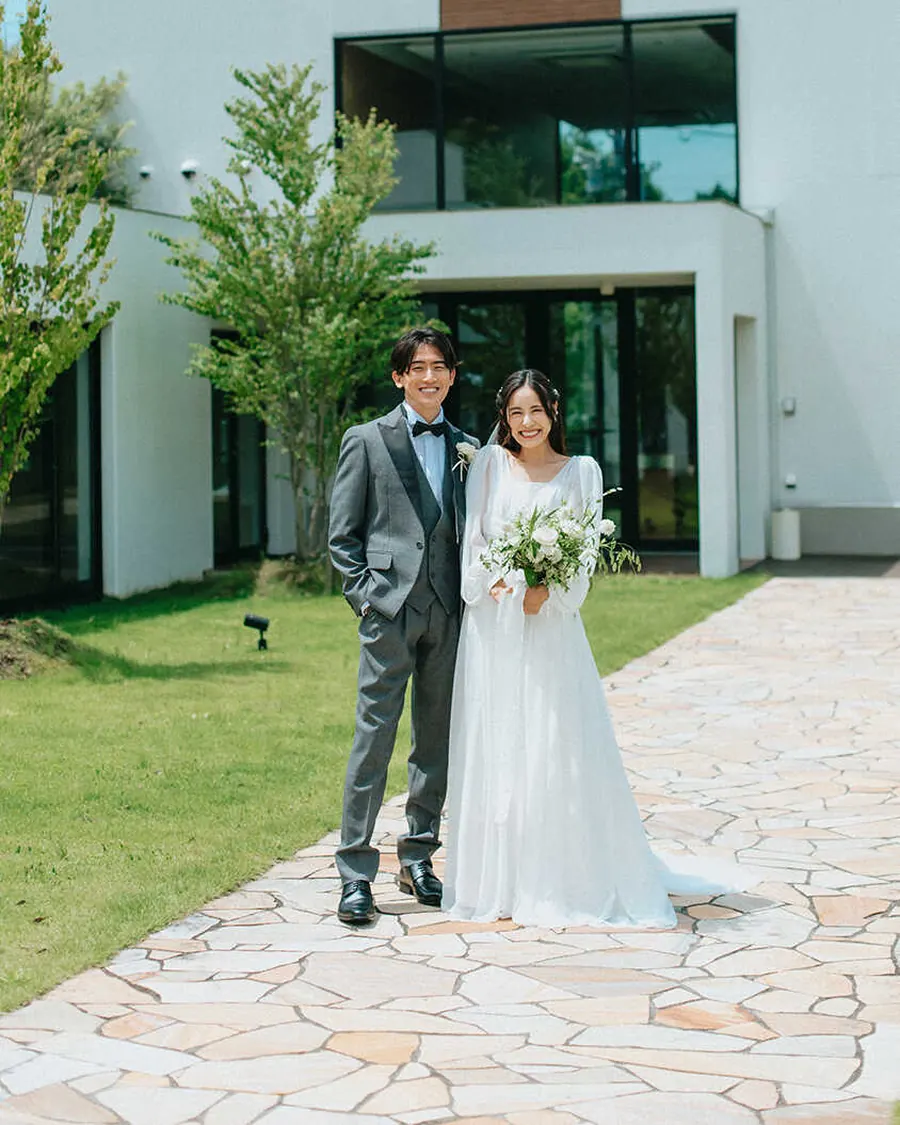 白い邸宅の前に立つ新郎新婦